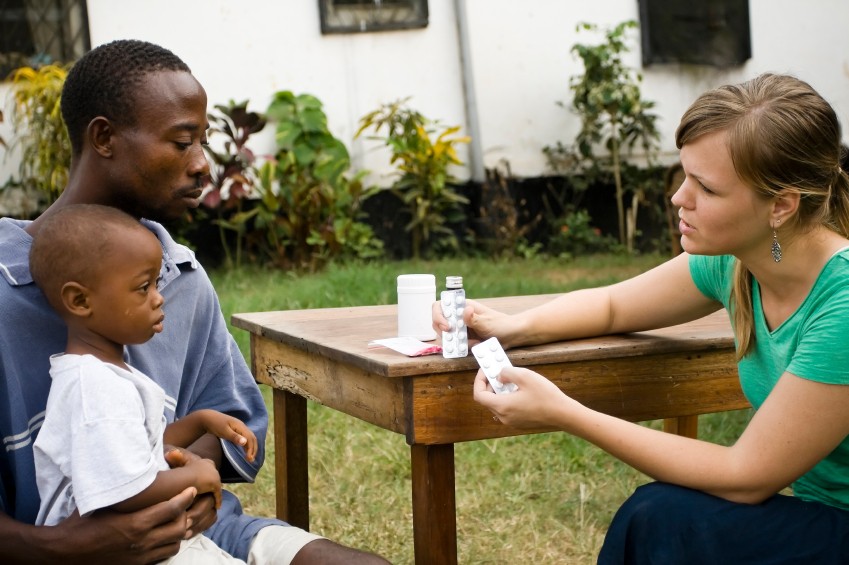 Healthcare volunteer discussing medicine with a parent and child in Kenya